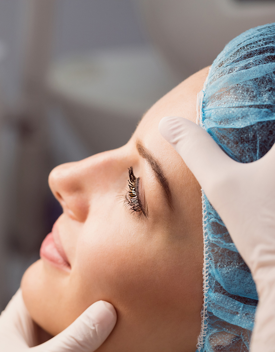 Hands of doctor examining womans face for cosmetic treatment at clinic